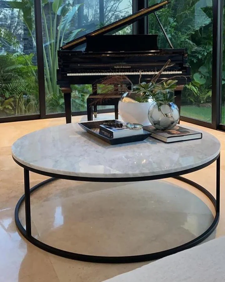 Mesa de centro redonda de mármol crema en sala con piano — Tempus Monterrey