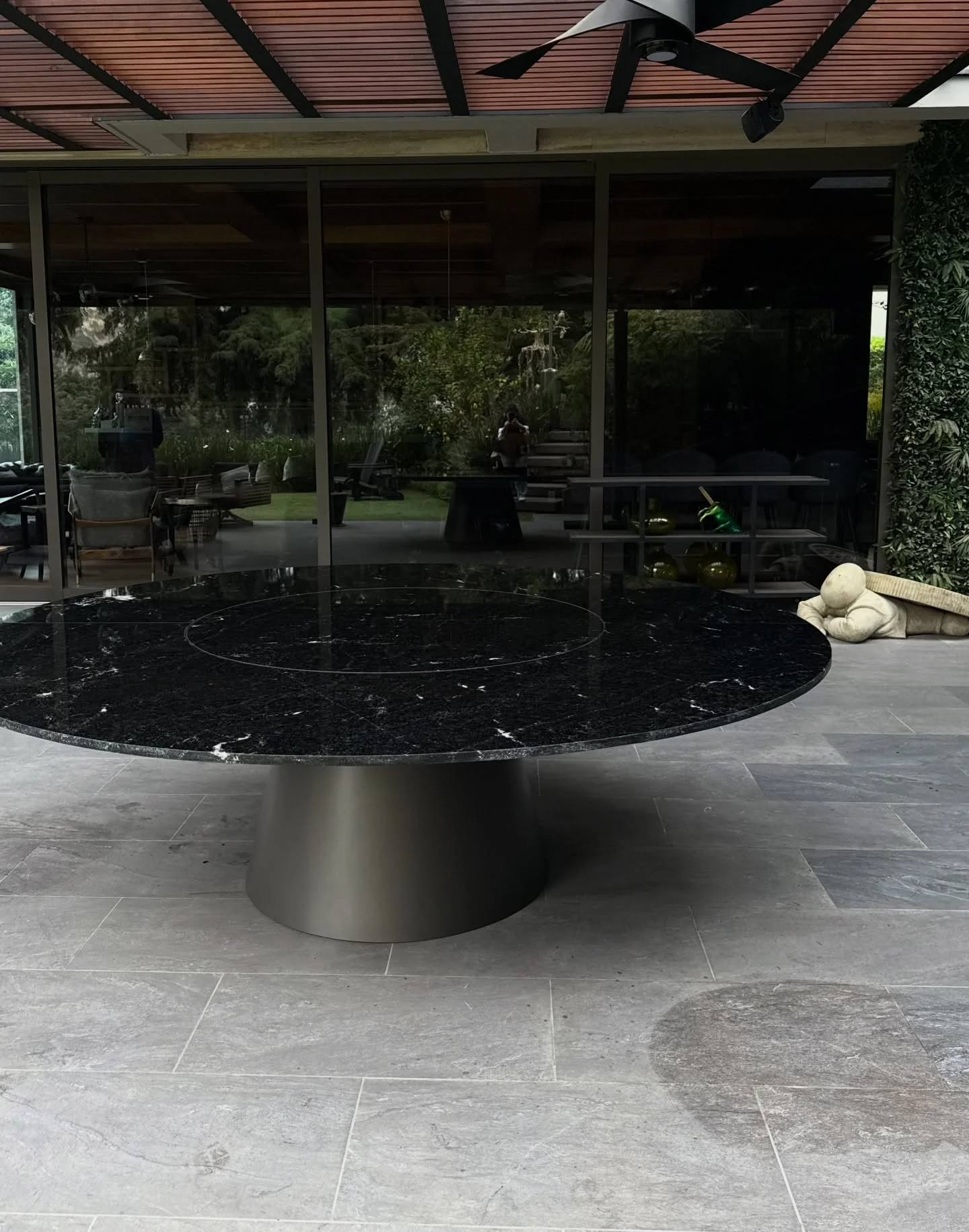 Mesa redonda de granito negro bajo pérgola exterior — Tempus Monterrey