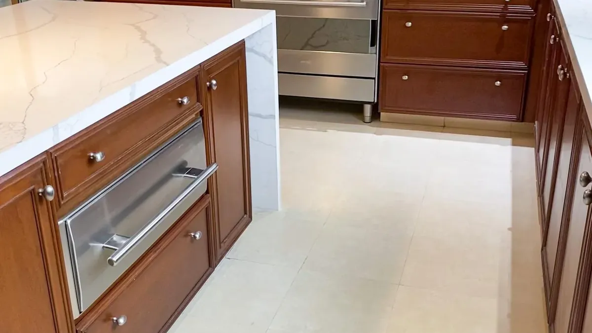 Cocina con cubierta e isla de piedra clara veteada, instalada por Tempus