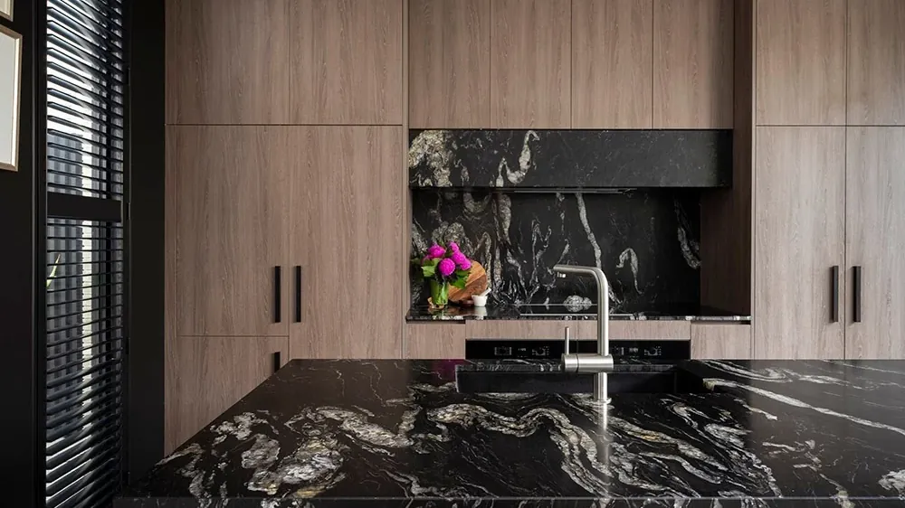 Isla de cocina con cubierta de piedra natural oscura con vetas blancas, fabricada e instalada por Tempus en Monterrey