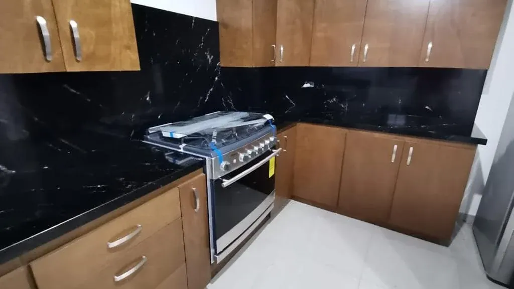 Cocina con cubierta y backsplash de piedra natural negra con vetas blancas, instalada por Tempus