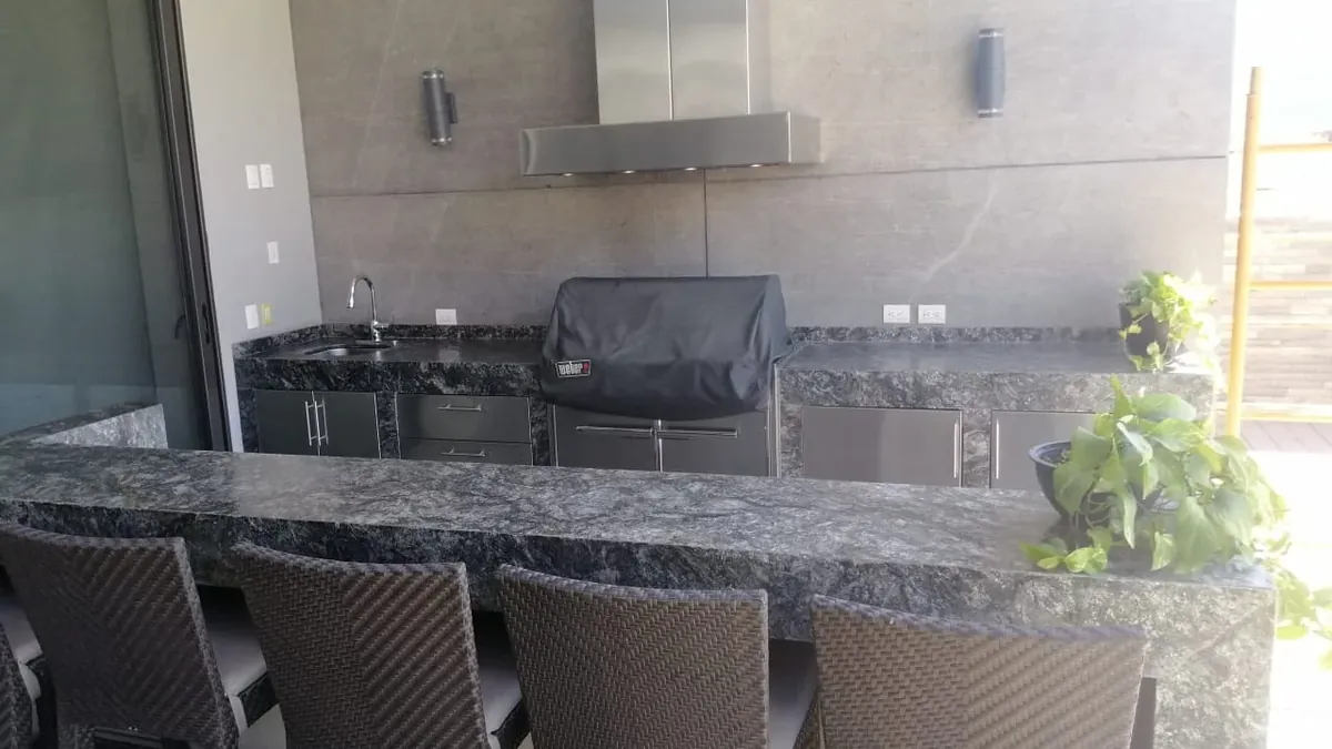 Cocina exterior con asador y barra de granito oscuro, fabricada e instalada por Tempus en Monterrey