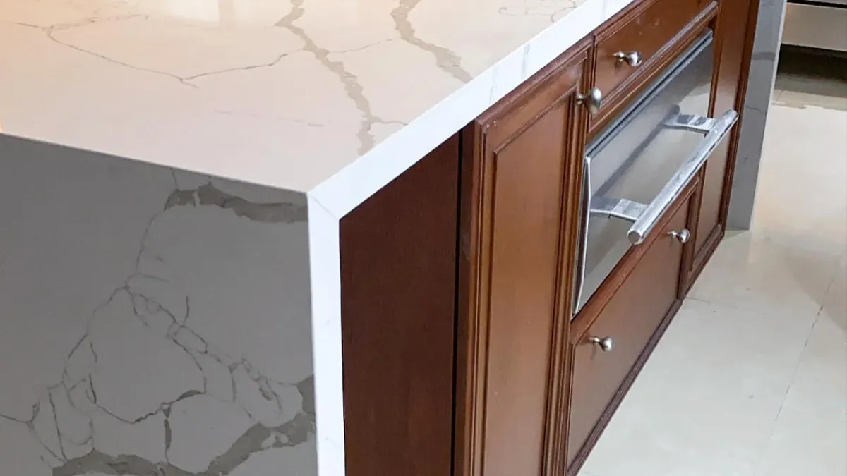 Isla de cocina en cascada con piedra blanca veteada, fabricada por Tempus