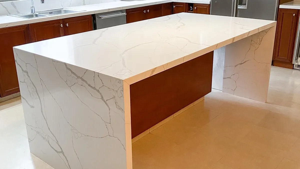 Isla de cocina en cascada con cubierta de piedra blanca veteada, fabricada e instalada por Tempus en Monterrey