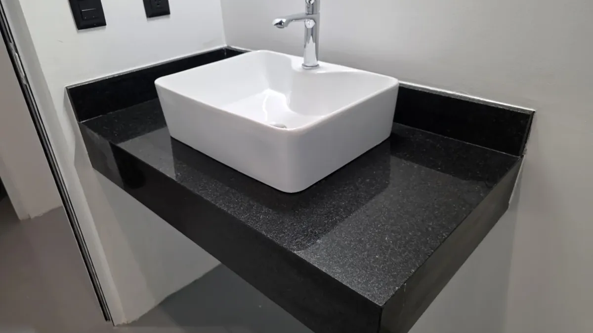 Cubierta de baño de granito negro con ovalín sobrepuesto blanco, instalada por Tempus
