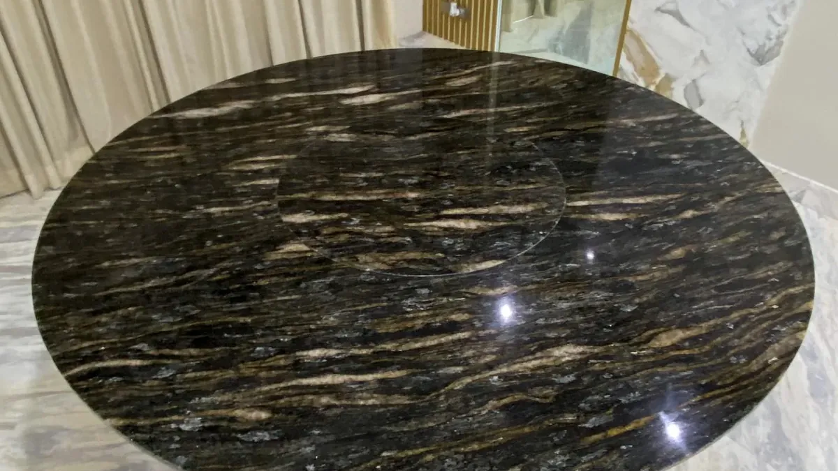 Mesa redonda con cubierta de piedra natural oscura, fabricada por Tempus