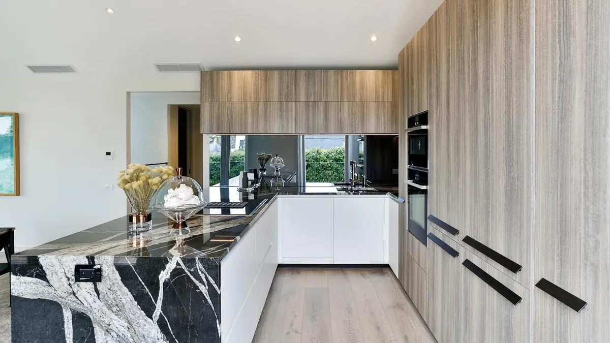 Cocina en U con cubierta de piedra natural negra con vetas blancas, instalada por Tempus