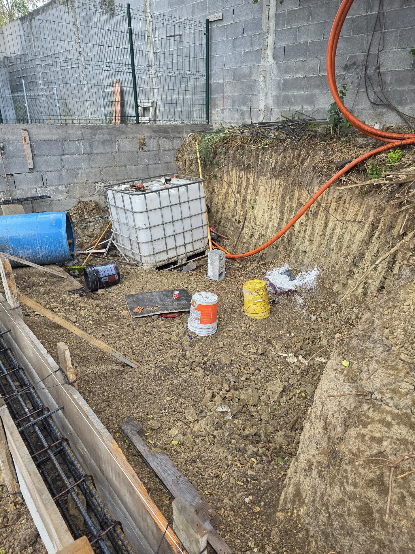 Rincón del lote con tinaco de agua y cubetas durante construcción — Casa Las Esmeraldas Tempus Monterrey