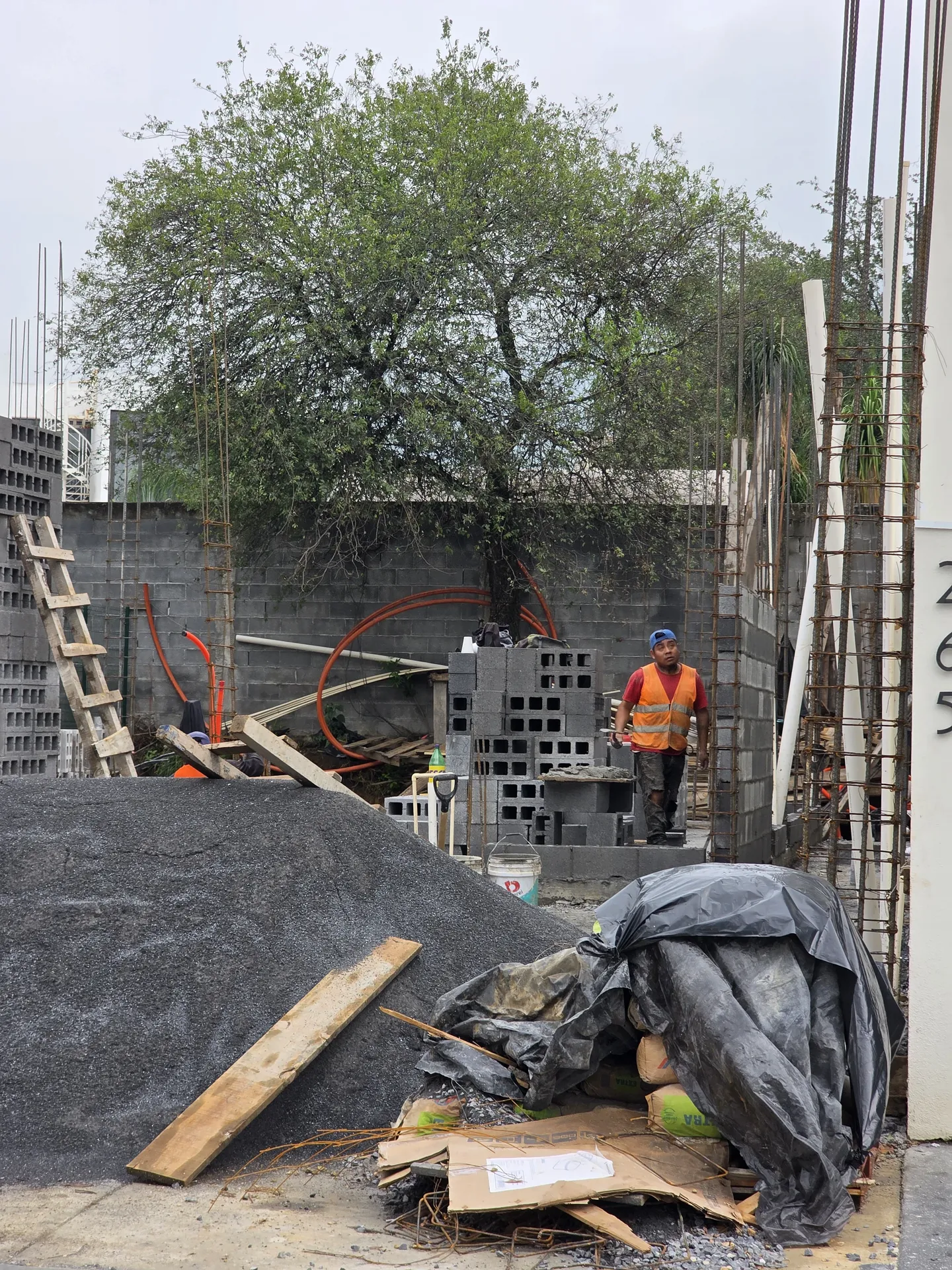 Trabajador con chaleco naranja entre muros de block recién iniciados — Casa Las Esmeraldas Tempus Monterrey