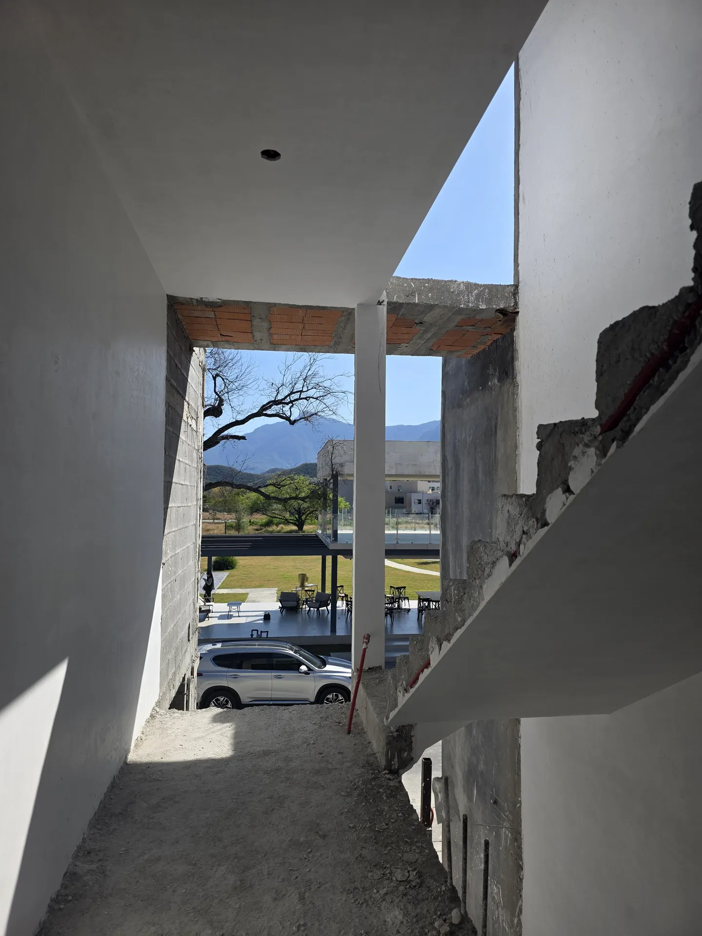 Pasillo de doble altura con vista a la calle y cerros al fondo — Casa Las Esmeraldas Tempus Monterrey