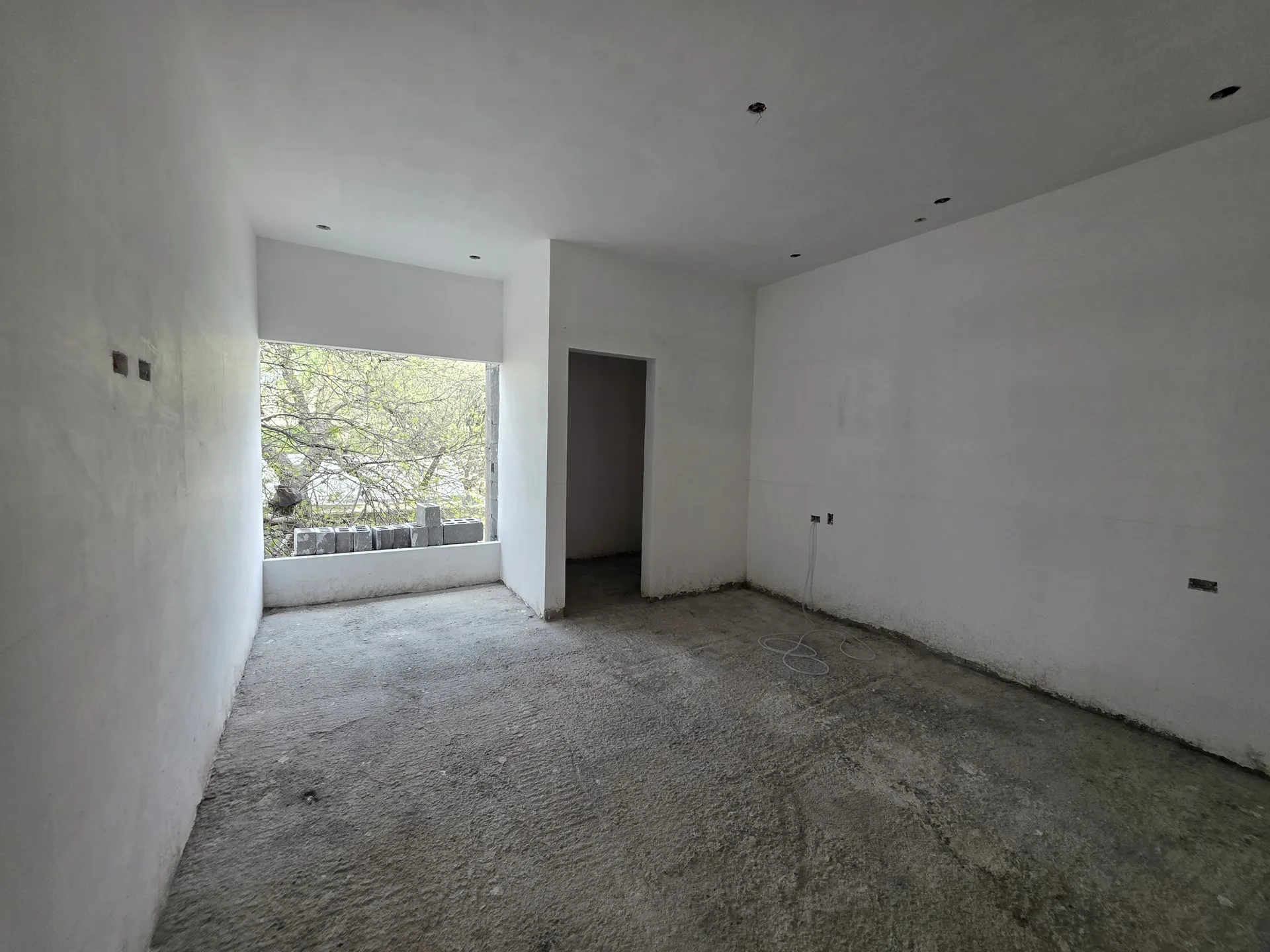 Habitación con muros aplanados y ventana lateral con vista al jardín — Casa Las Esmeraldas Tempus Monterrey