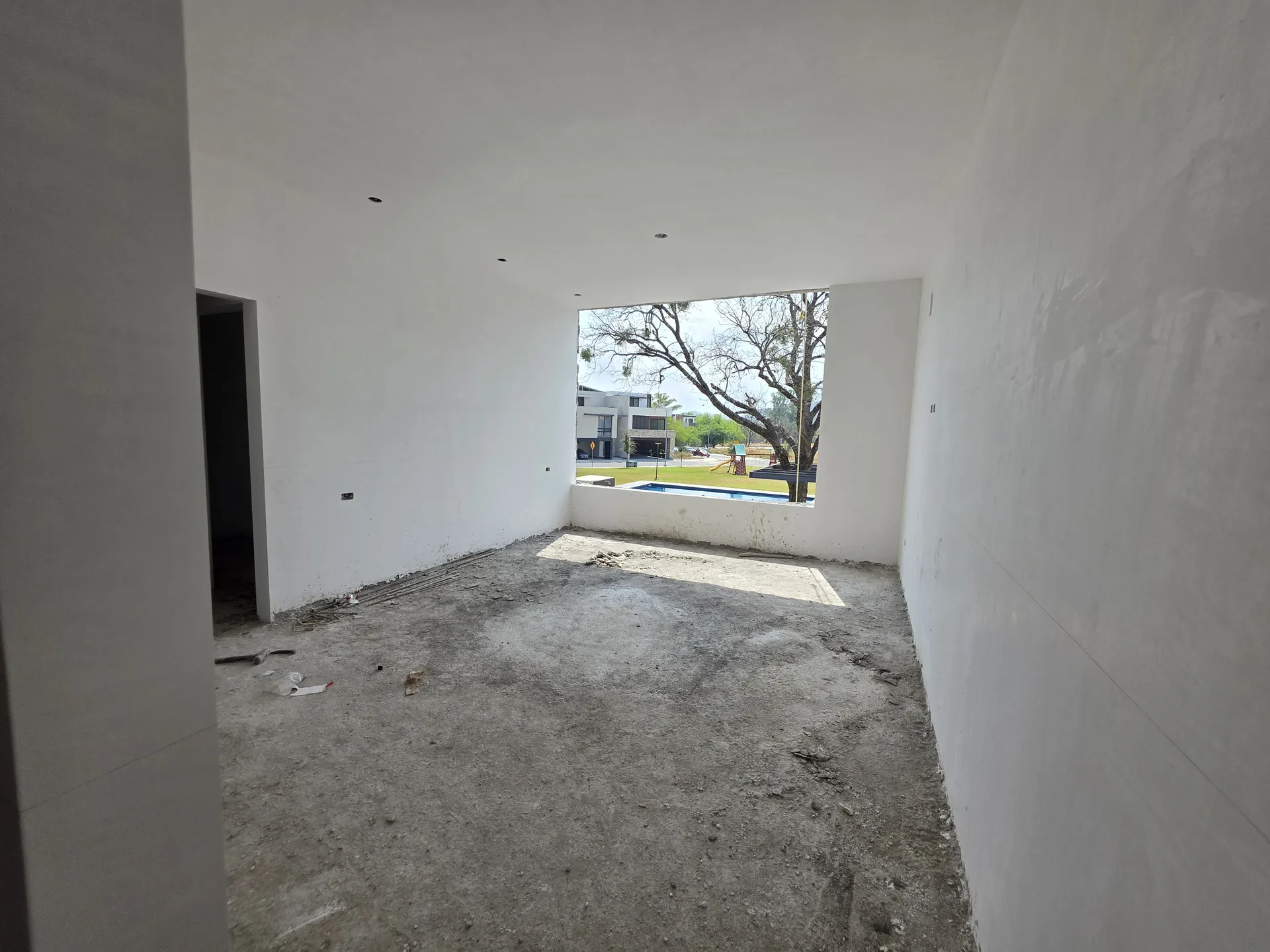 Sala amplia con ventana panorámica hacia casas vecinas y árboles — Casa Las Esmeraldas Tempus