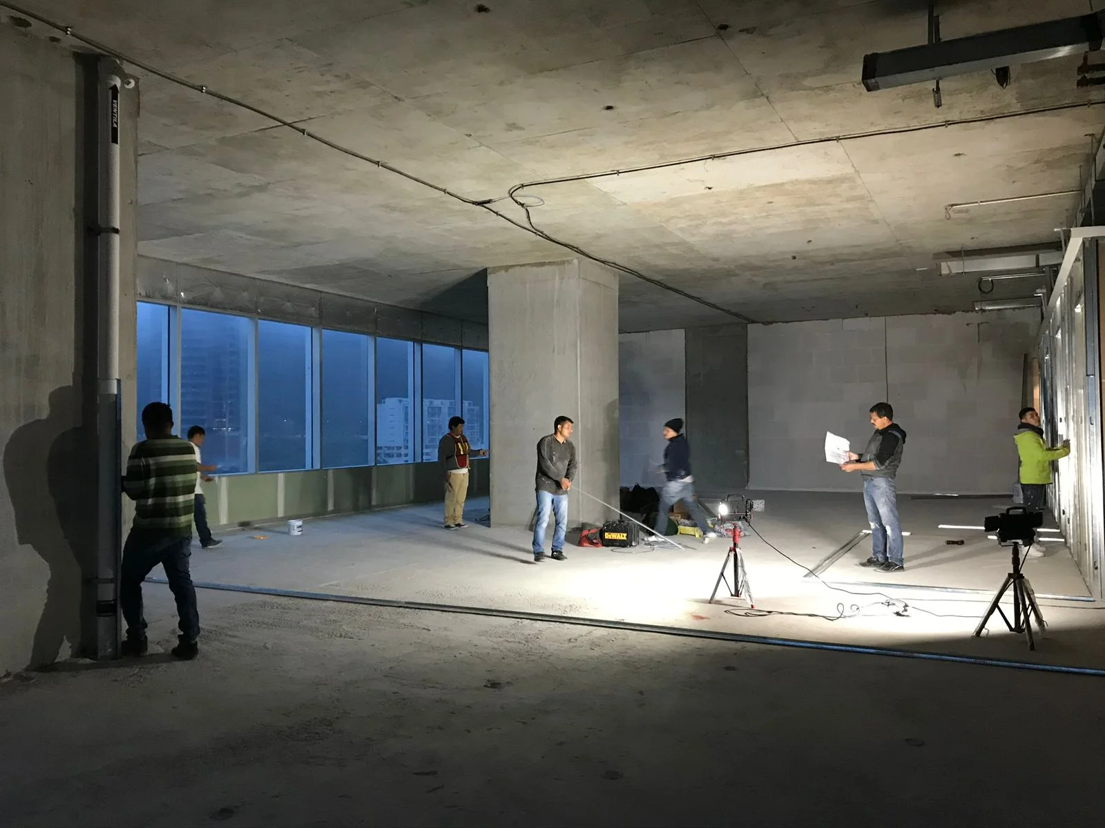 Reunión técnica con planos en obra nocturna con vista a edificios corporativos — Altos del Roble Tempus