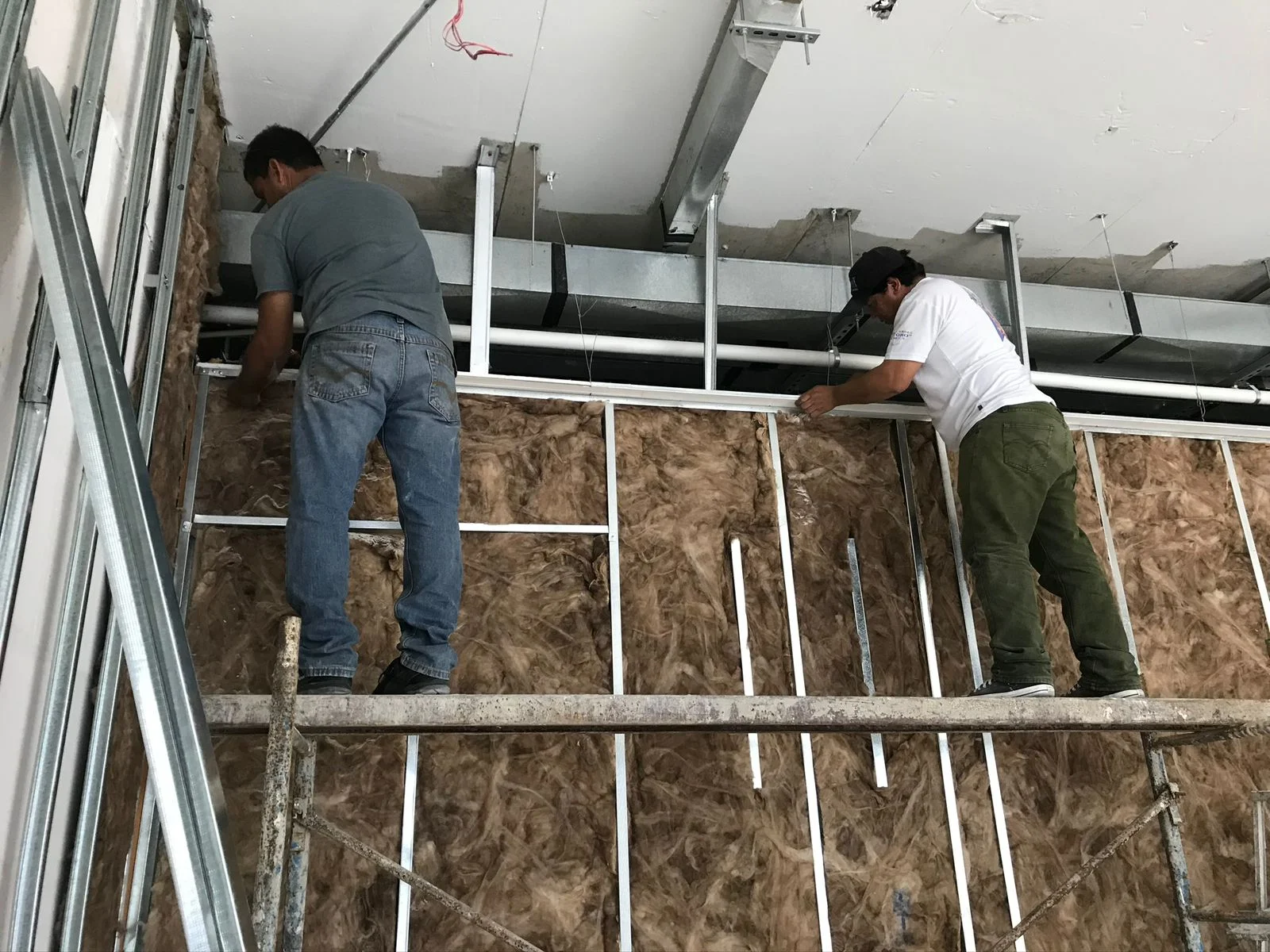 Trabajadores sobre andamio instalando muros divisorios con OSB y perfilería — Altos del Roble Tempus
