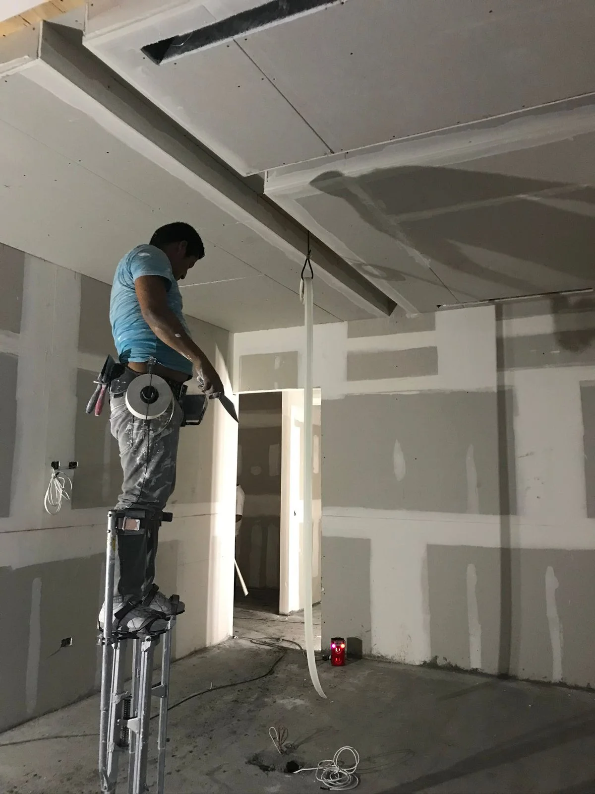 Trabajador con zancos profesionales instalando plafón acústico — Altos del Roble Tempus Monterrey