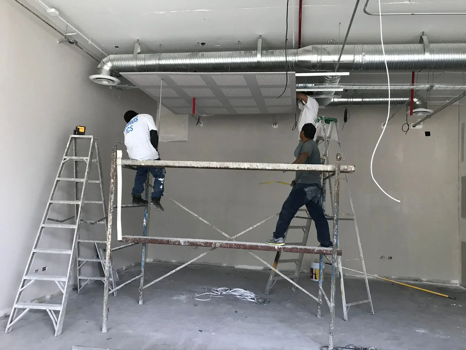 Trabajadores sobre andamio instalando ductería de aire acondicionado en plafón — Altos del Roble Tempus