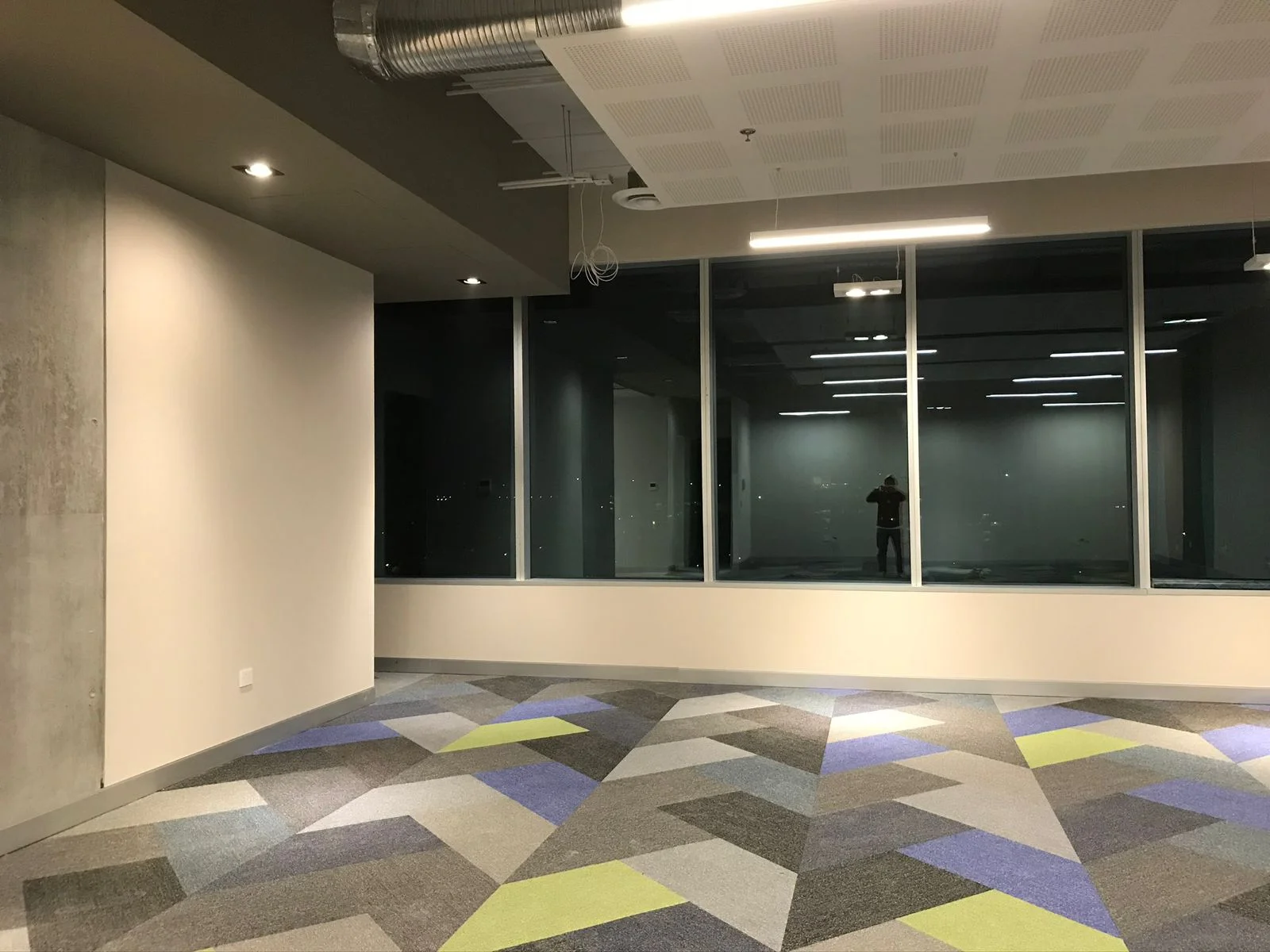 Sala de juntas terminada con cancelería de cristal y alfombra modular geométrica — Altos del Roble Tempus
