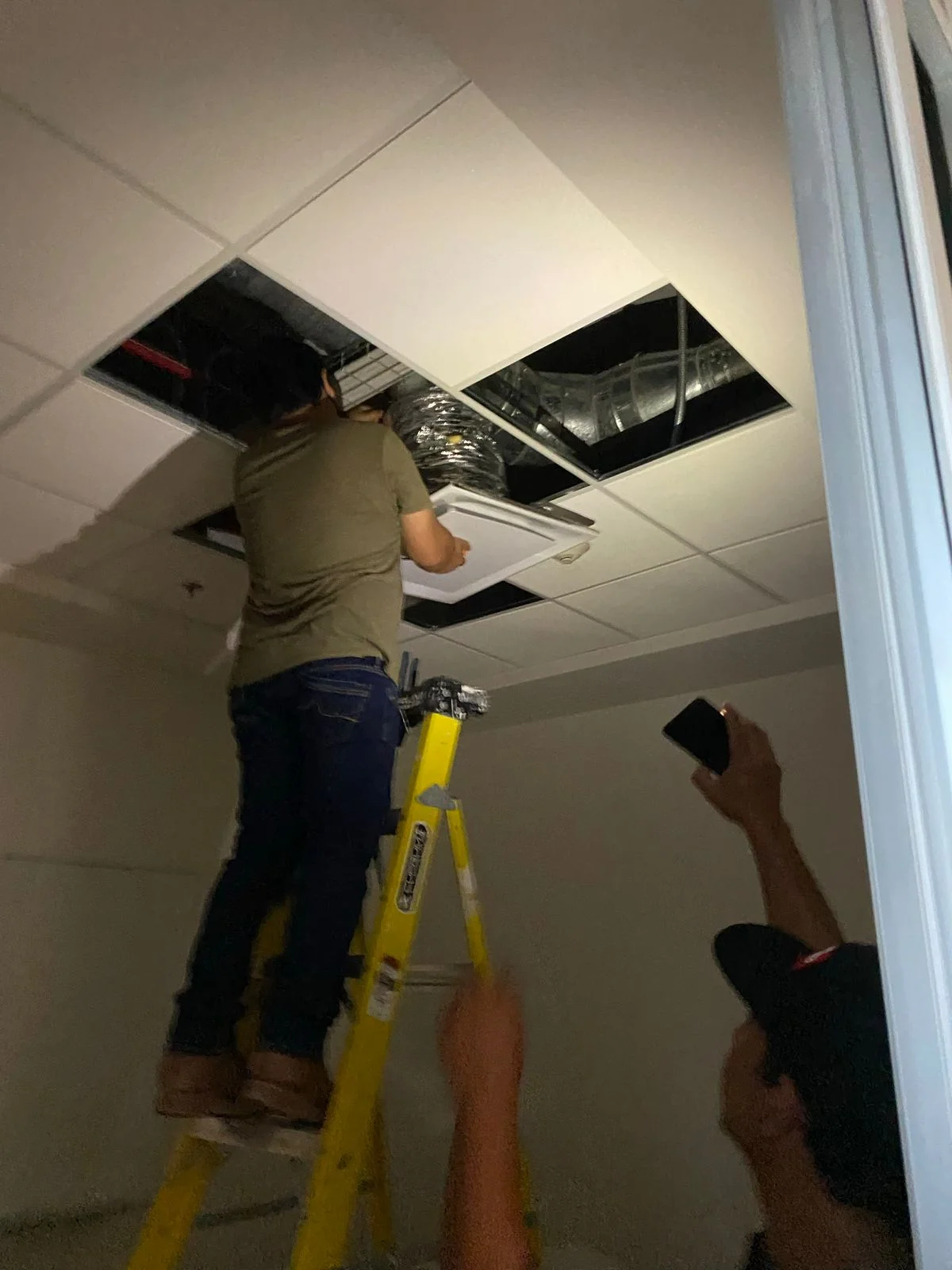 Trabajador instalando rejilla difusora de aire acondicionado en plafón modular tegular — Nórdika Business Center Tempus