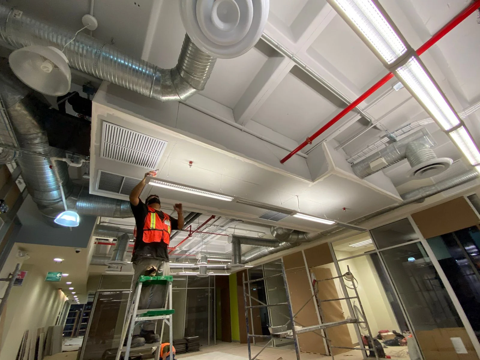 Trabajador ajustando rejilla de difusión HVAC en plafón con desnivel — Nórdika Business Center Tempus Monterrey