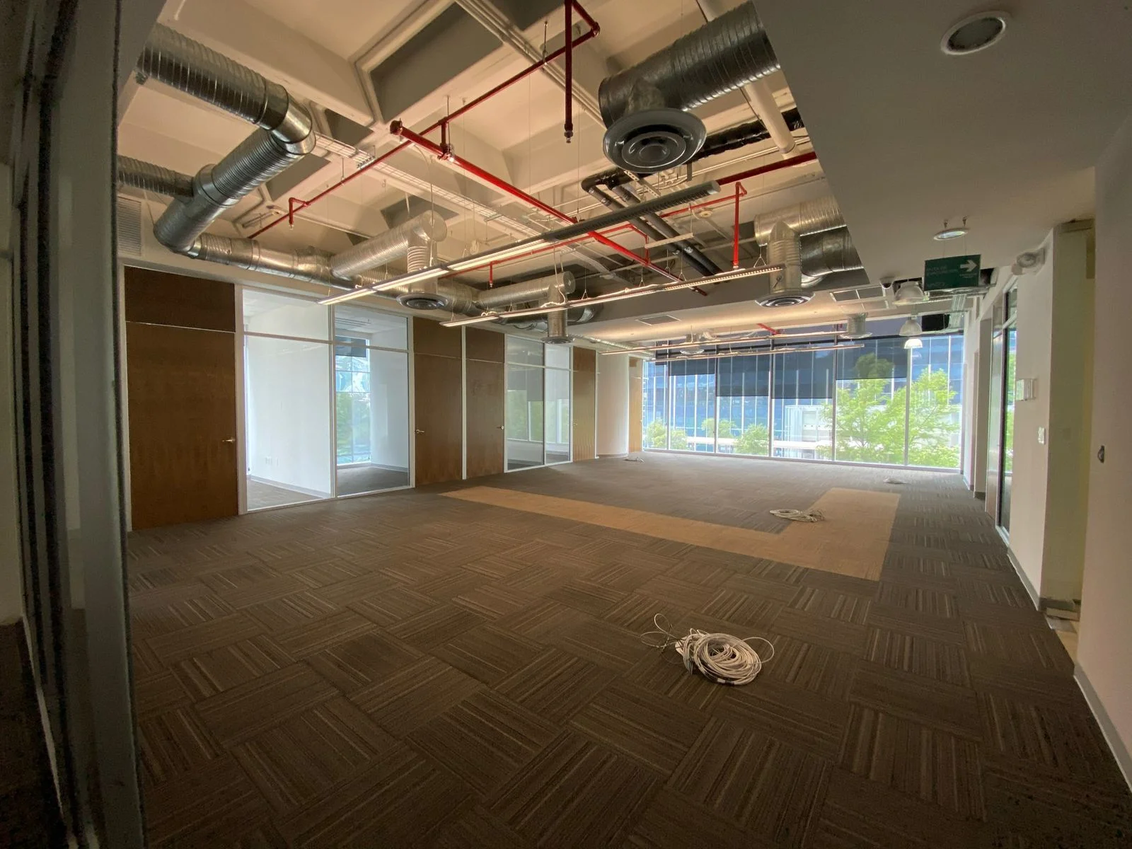 Open office vacío con ductería HVAC roja y vista a edificios corporativos — Nórdika Business Center Tempus