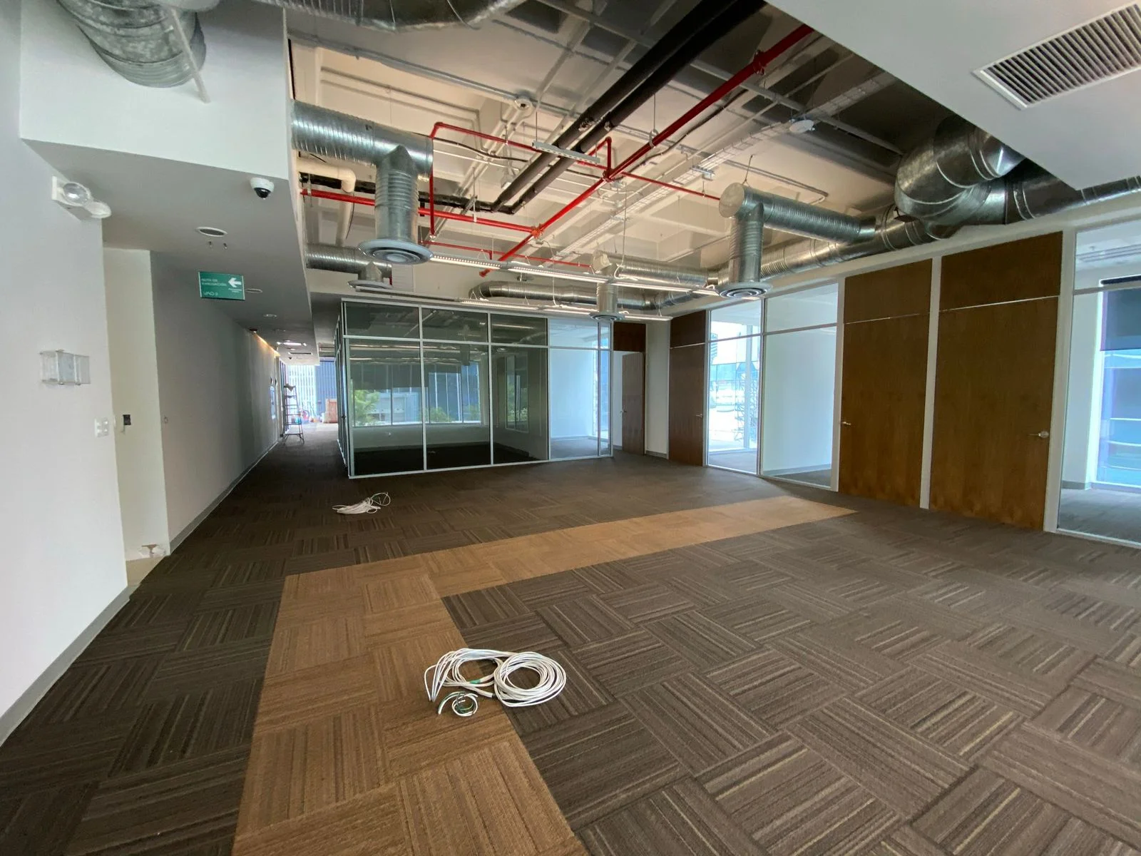 Espacio amplio con cancelería de cristal y ductería metálica vista — Nórdika Business Center Tempus