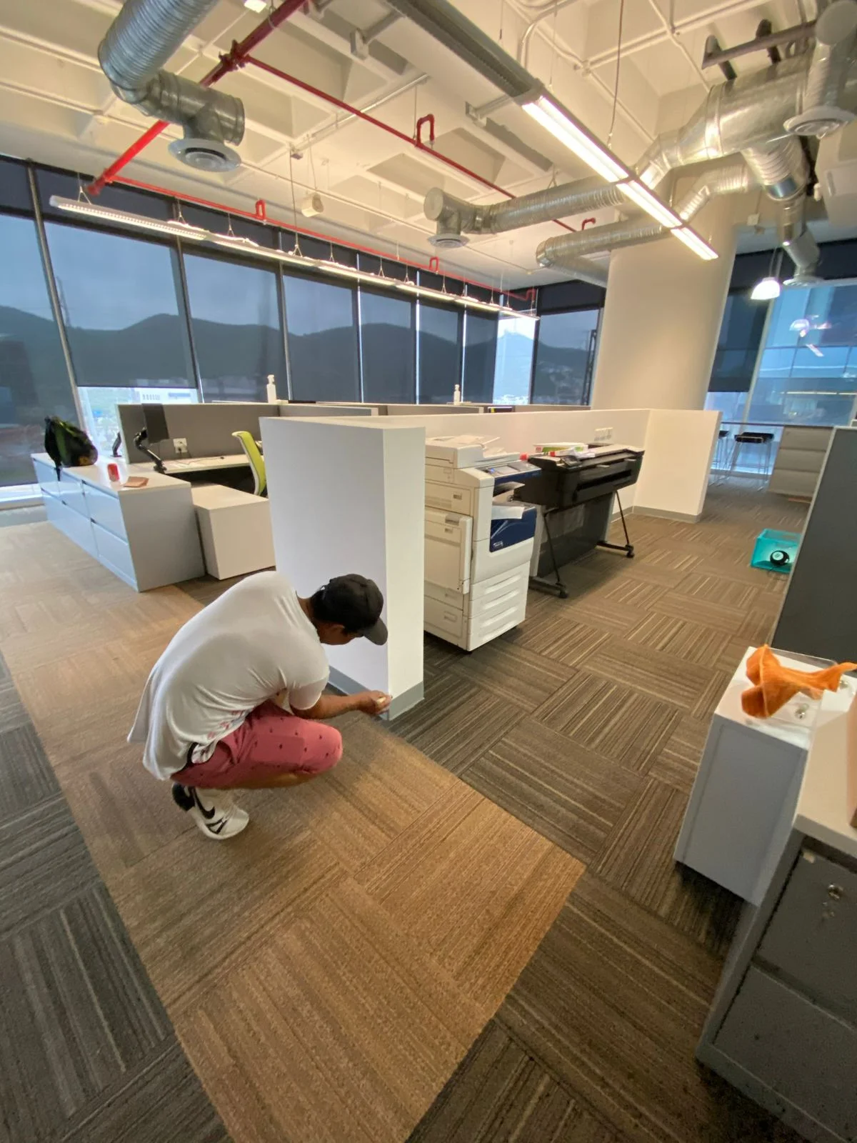Trabajador aspirando alfombra modular en open office terminado — Nórdika Business Center Tempus