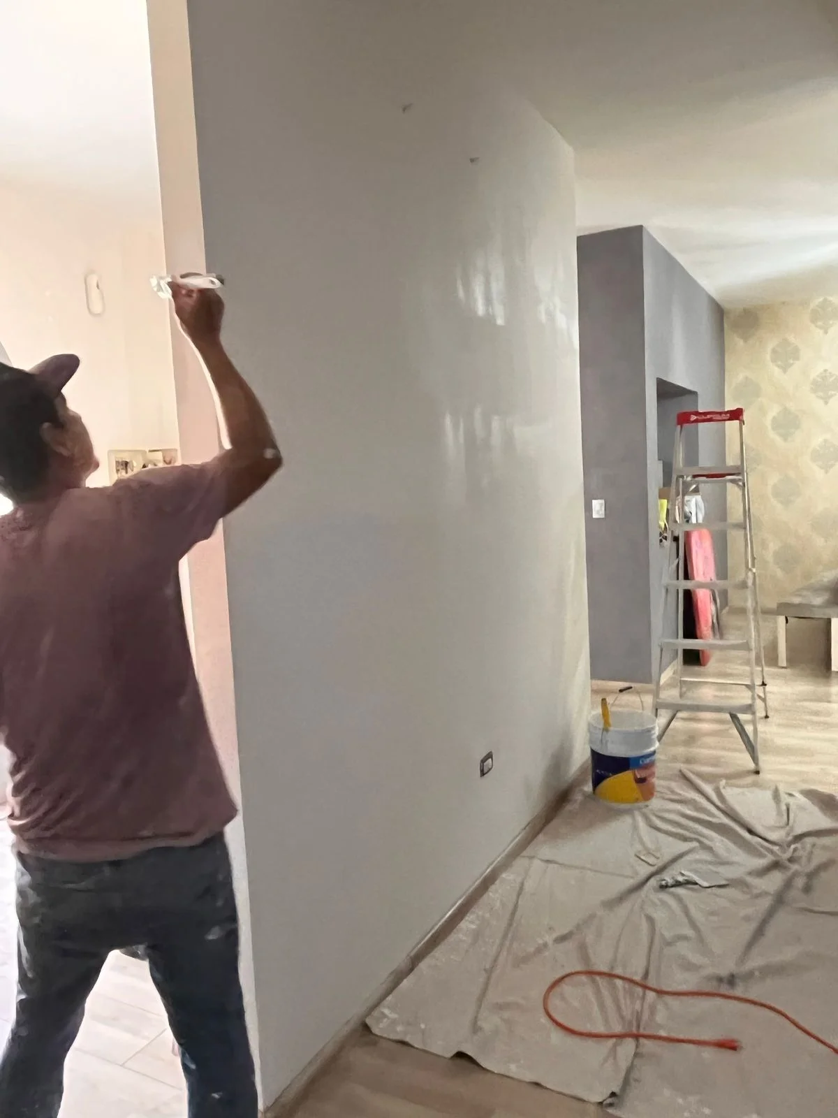 Trabajador resanando muro con bote de pintura Comex y escalera — Nórdika Business Center Tempus