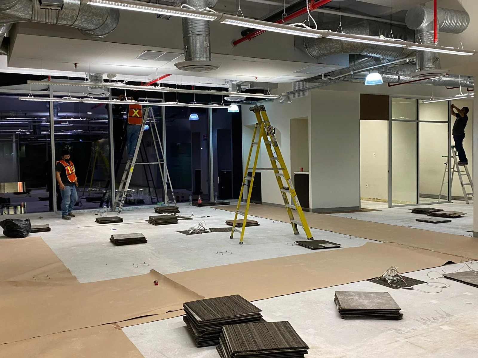 Pilas de baldosas de alfombra modular en proceso de instalación con andamio amarillo — Nórdika Business Center Tempus