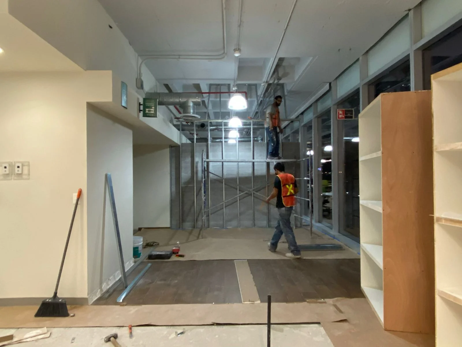Pasillo en proceso con trabajadores en andamio y lámparas pendant decorativas — Nórdika Business Center Tempus