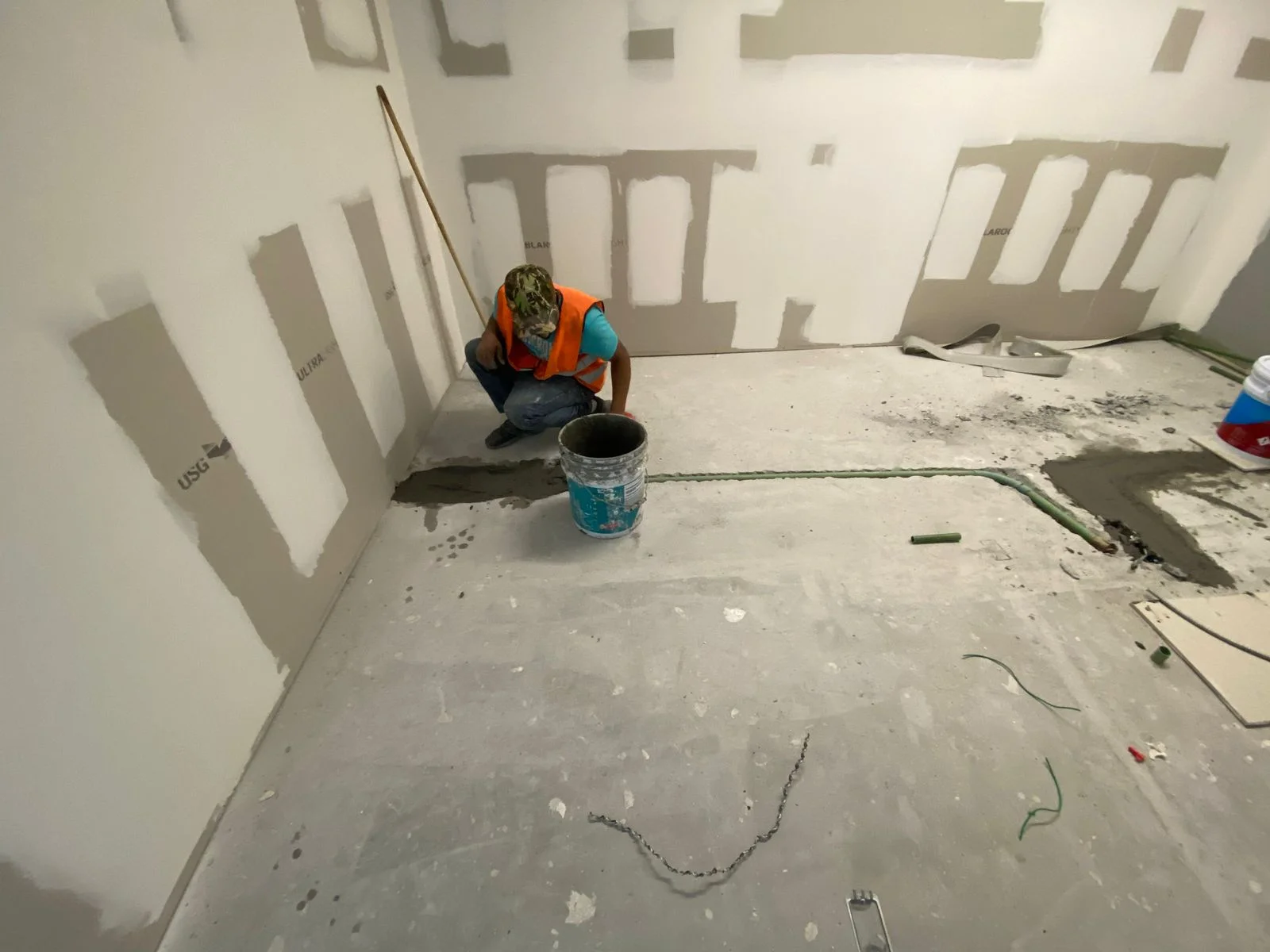 Cuarto con tablaroca USG Ultra Core resanada y trabajador con chaleco revisando muros — Nórdika Business Center Tempus