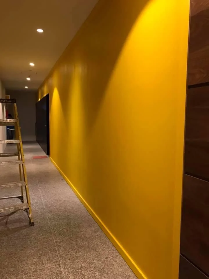 Pasillo terminado con muro acentuado amarillo intenso y madera de nogal lateral — Nórdika Business Center Tempus