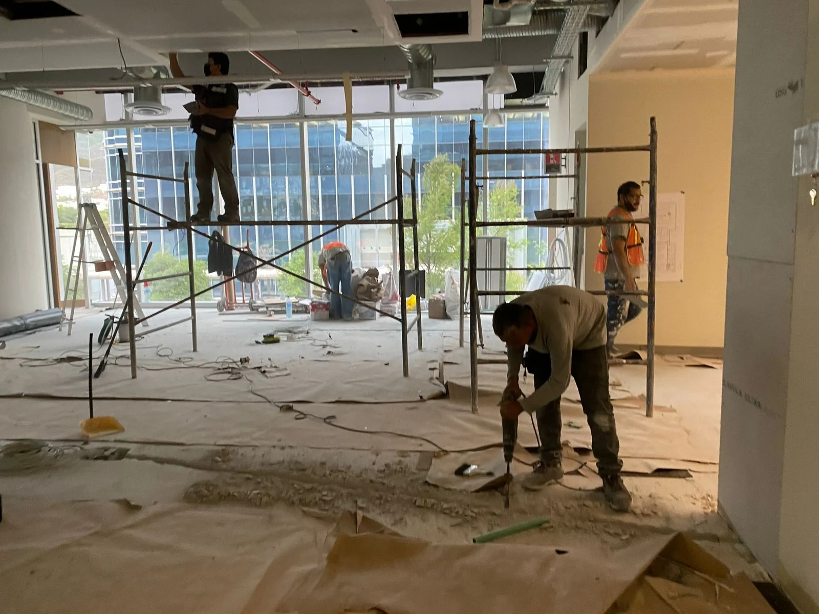 Trabajadores demoliendo concreto en obra con vista a edificios corporativos de cristal — Nórdika Business Center Tempus
