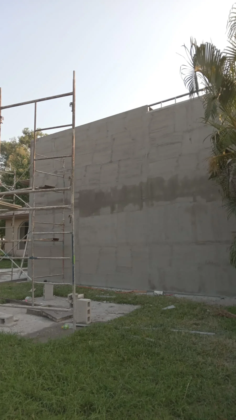 Muro exterior alto con aplanado en proceso y andamio metálico — Privada Montealto Tempus Monterrey