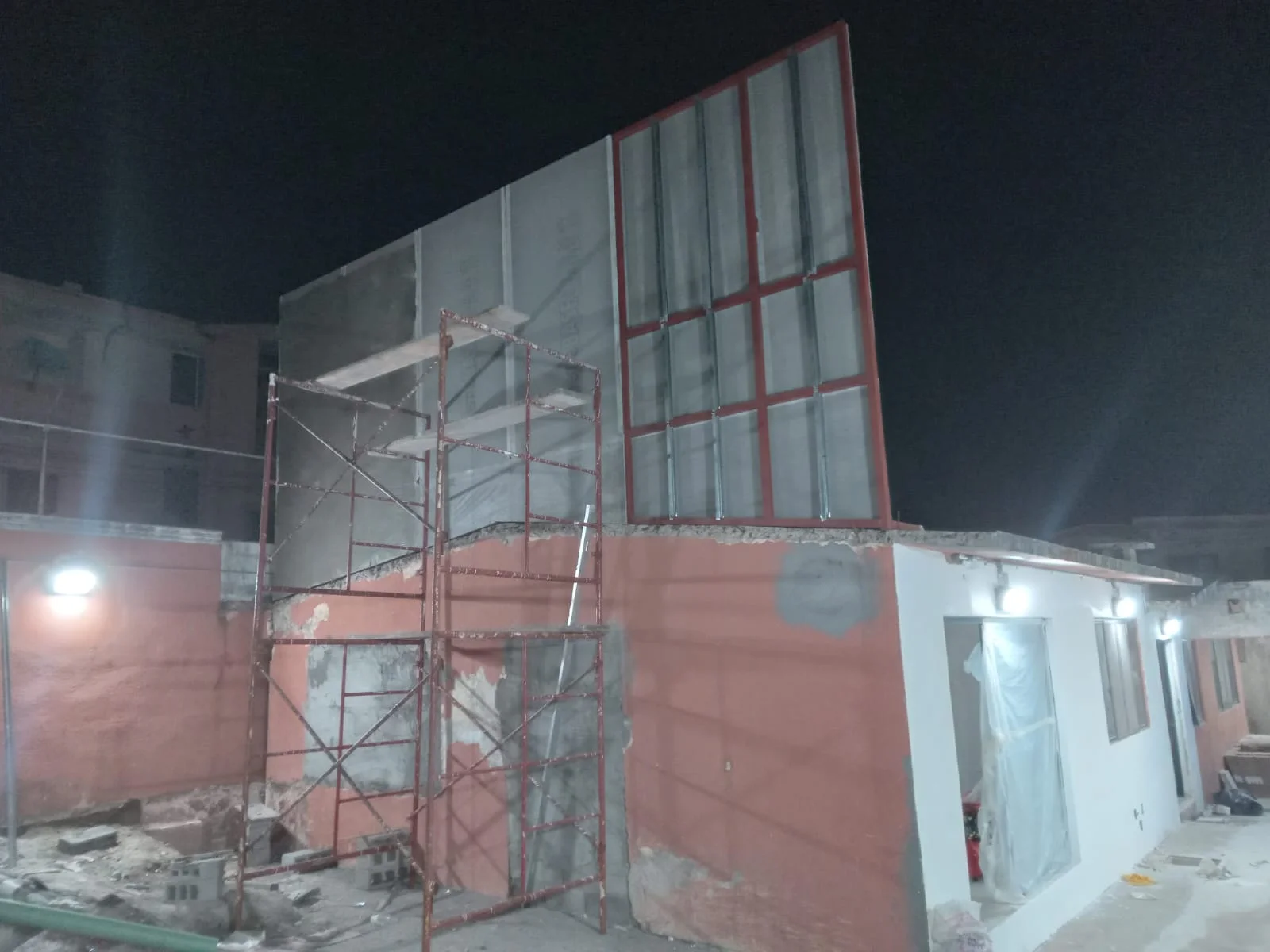 Vista nocturna de muro alto cementicia con ventana enmarcada en perfilería roja — Privada Montealto Tempus