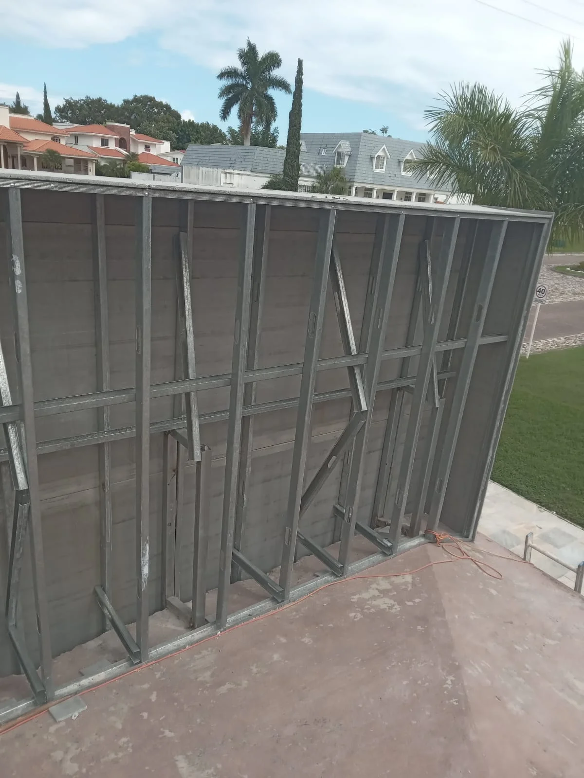 Muro alto exterior con paneles cementicia gris entre perfilería metálica vertical — Privada Montealto Tempus